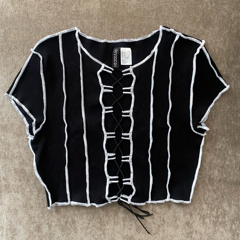 Black lace-up front crop top (center is open) with white contrast stitching.